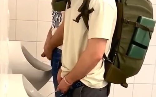 Handsome traveller peeing at urinals