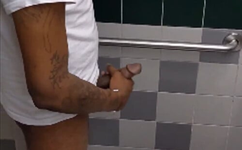 Hung black dude caught stroking his cock in public toilet