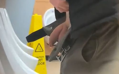 Handsome man squeezing his dick at urinals