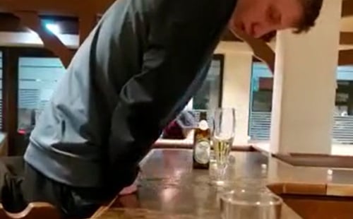Drunk dude pissing over a bar in public